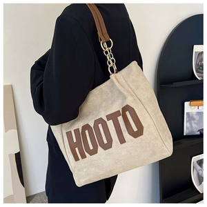 Détail du sac cabas en toile avec patch cuir HOOTO et bandoulière en chaîne métallique