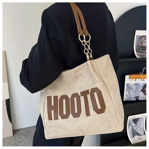 Détail du grand sac cabas beige avec écusson HOOTO et anse en chaîne dorée et cuir