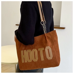 Détail du patch en cuir HOOTO et bandoulière chaîne sur sac cabas en suède marron