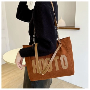 Détail du sac cabas en daim marron avec lettrage HOOTO et bandoulière chaîne