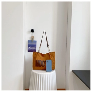 Sac fourre-tout en daim marron avec logo HOO et chaîne dorée, montré avec un smartphone