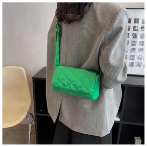 Détail de vue arrière d'un sac bandoulière matelassé en nylon vert vif porté par un modèle