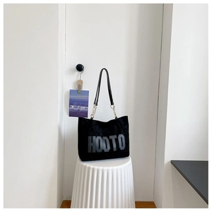 Détail du sac cabas en daim noir avec logo HOOTO et bandoulière chaîne dorée
