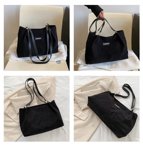 Detailed view of black corduroy tote bag featuring striped texture and small fashion label