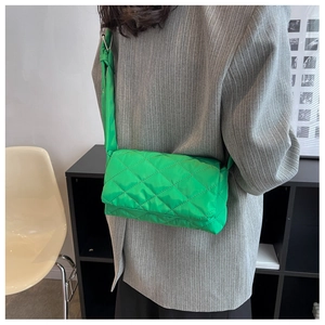 Détail du sac bandoulière en nylon vert vif avec surpiqûres losanges sur blazer gris