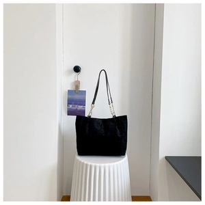 Détail du sac cabas en daim noir avec chaîne en métal doré et bandoulière cuir