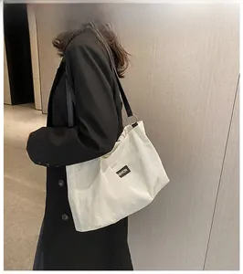 Detail of corduroy tote bag showing striped texture and black leather shoulder strap