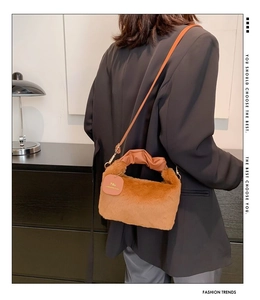 Detailed view of brown plush crossbody bag with leather strap and 'You' tag detail