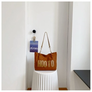 Détail du sac cabas en daim marron avec lettrage HOOTO doré et fine bandoulière chic