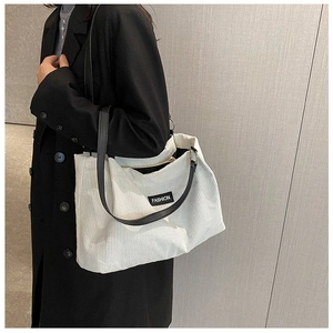 Detail of white corduroy tote bag featuring vertical stripes and black fashion leather patch