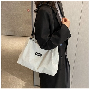Detail of off-white corduroy tote bag showing striped texture and fashion brand label