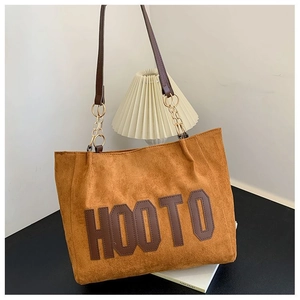 Détail d'un sac cabas en daim marron avec appliqué HOOTO et bandoulière à chaîne