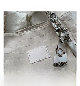 Close-up of woven beige tote bag featuring a decorative silk scarf and leather patch detail