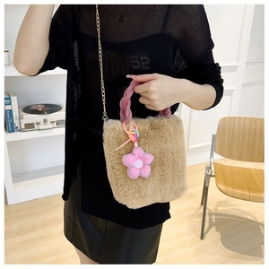 Détail du sac seau en peluche camel avec poignée tissée rose et breloque fleur
