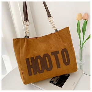 Détail du sac cabas en daim marron avec bandoulière chaîne dorée et logo HOOTO
