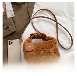 Close-up of brown plush faux fur handbag with leather straps and pleated handle detail