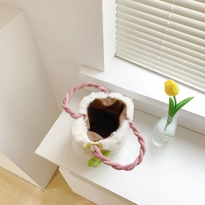 Vue détaillée du sac seau en peluche blanche avec anses tissées roses et doublure