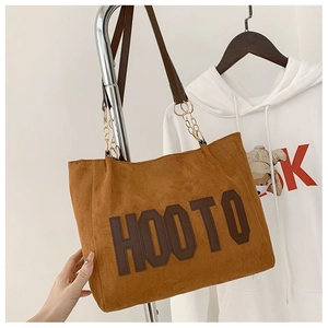 Gros plan d'un sac cabas en daim marron avec lettrage HOOTO et bandoulière dorée