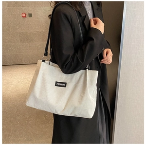 Detail of white corduroy tote bag showing textured fabric and fashion label accent