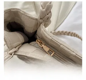 Detail of light gold metal zipper and woven texture on a cream quilted tote bag