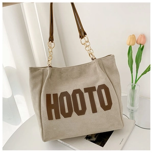 Détail du cabas en daim beige avec patch HOOTO et bandoulière en chaîne métal