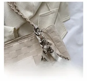 Detail of light beige woven tote bag with a decorative silk scarf tied on the strap handle