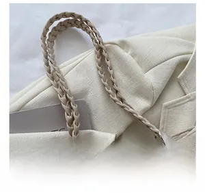 Detail of woven beige tote bag featuring braided shoulder straps and decorative silk scarf