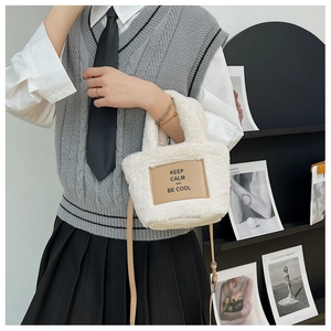 Furry white plush crossbody bag with lettered leather patch shown on model
