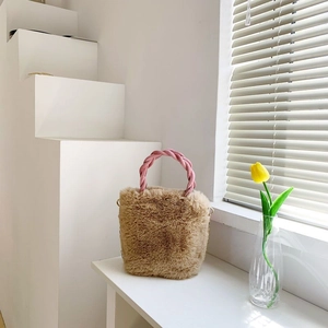 Détail d'un sac seau en peluche marron avec anse tressée rose et anneaux en métal