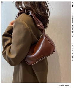 Brown leather baguette bag with pleated shoulder strap and vintage gold lettering