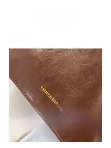 Close-up of brown litchi pattern leather tote bag showing fine stitching and gold logo