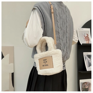 Detail of white plush bucket bag with brown leather patch and adjustable crossbody strap