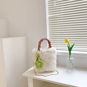 Détail du sac en fausse fourrure blanche avec anse tressée rose et breloque fleur