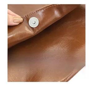 Detail of magnetic snap closure on brown pebbled leather tote bag with neat stitching