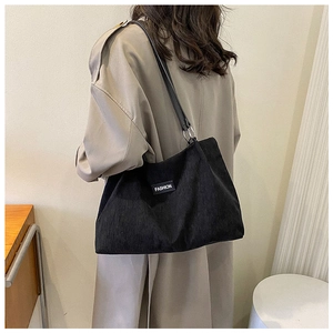 Detail of black corduroy tote bag showing soft ribbed texture and leather shoulder strap