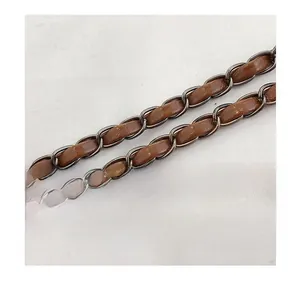 Detail of woven chain shoulder strap made of bronze metal and brown leather material