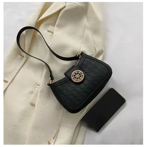 Detail shot of black quilted shoulder bag with golden rudder clasp and phone for scale