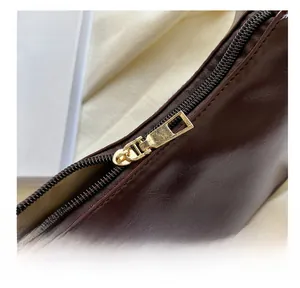 Macro detail of smooth gold zipper hardware and dark brown leather texture on shoulder bag