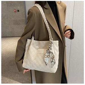 Close-up of cream woven tote bag featuring decorative silk scarf and side logo tag