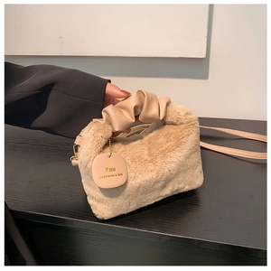 Close-up of beige faux fur handbag with ruched leather handle and stylish brand tag