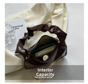 Internal capacity of dark brown pleated baguette bag showing phone and wallet