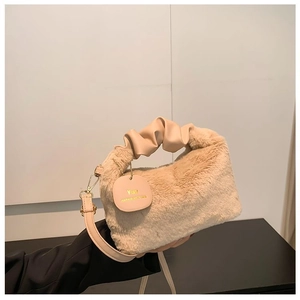 Detail of beige plush handbag featuring ruched leather handle and adjustable strap