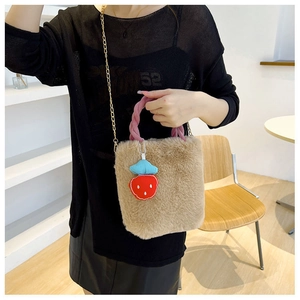 Détail d'un sac seau en peluche avec poignée tressée rose et breloque fraise