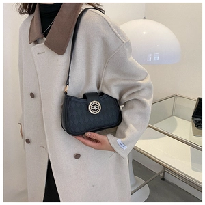 Detail of black quilted shoulder bag featuring a stylish gold round metal clasp closure