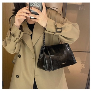 Mirror selfie showing the shiny black leather tote bag with a gold chain strap detail