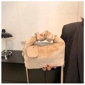 Detail of beige plush handbag featuring ruched handle and pink designer brand tag