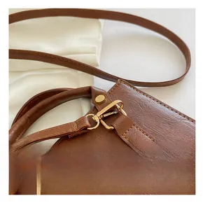 Dettaglio macro della borsa in pelle marrone con hardware dorato e cuciture raffinate