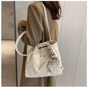 Close-up of cream quilted tote bag with decorative silk scarf and woven texture strap