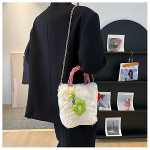 Détail d'un sac seau en peluche blanc avec poignée tissée rose et breloque fleur verte
