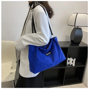 Detail of Klein Blue corduroy tote bag featuring a black 'FASHION' label and leather straps
